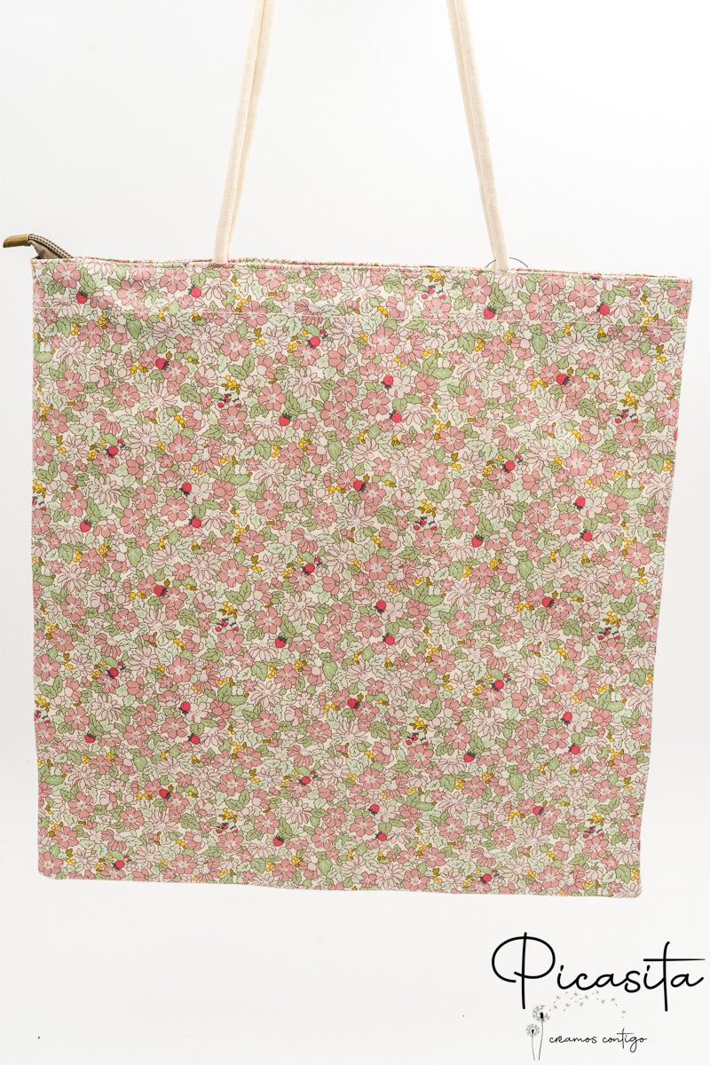 Bolsa de tela tipo tote bag con estampado de flores rosas y asas de cuerda blanca.