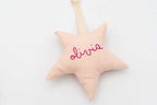Estrella de tela rosa con el nombre olivia en el frontal y cinta para colgar