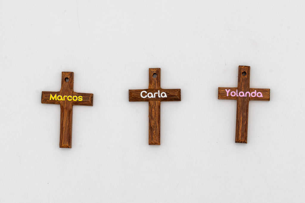 Tres cruces pequeñas de madera oscura con nombres personalizados