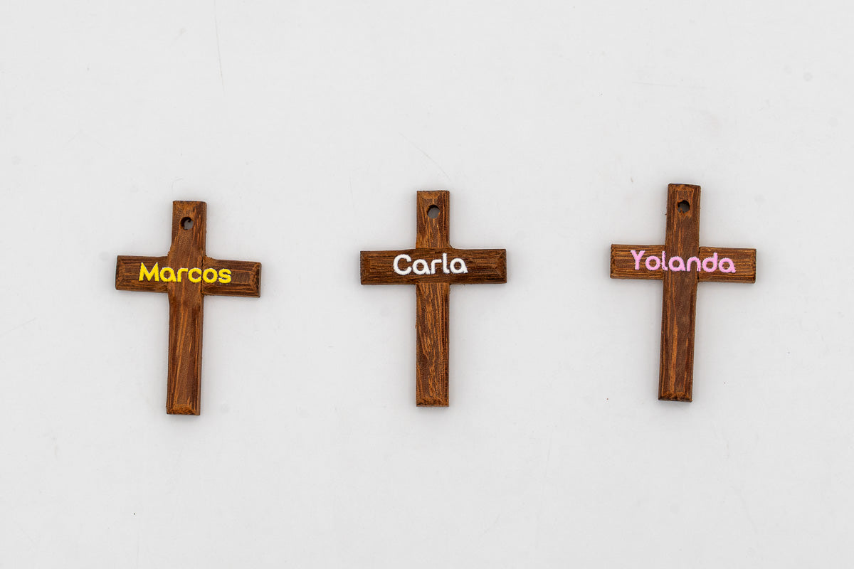 Tres cruces pequeñas de madera oscura con nombres personalizados
