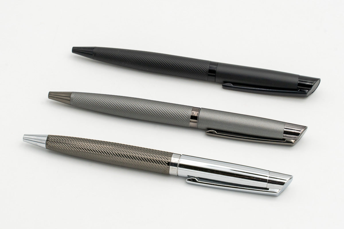 Stylos en métal noir, gris et argenté vus en diagonale.