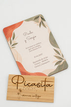 Faire-part de mariage en bois avec des feuilles dans des tons terracotta et vert sauge