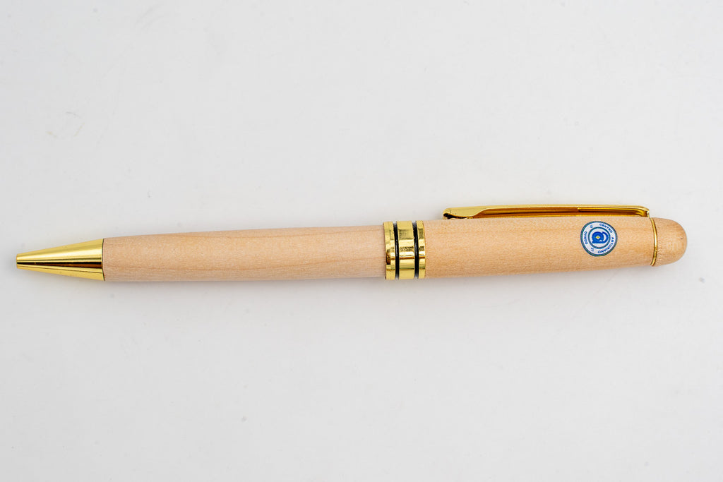 Stylo en bois clair avec emblème circulaire en couleur et détails dorés.