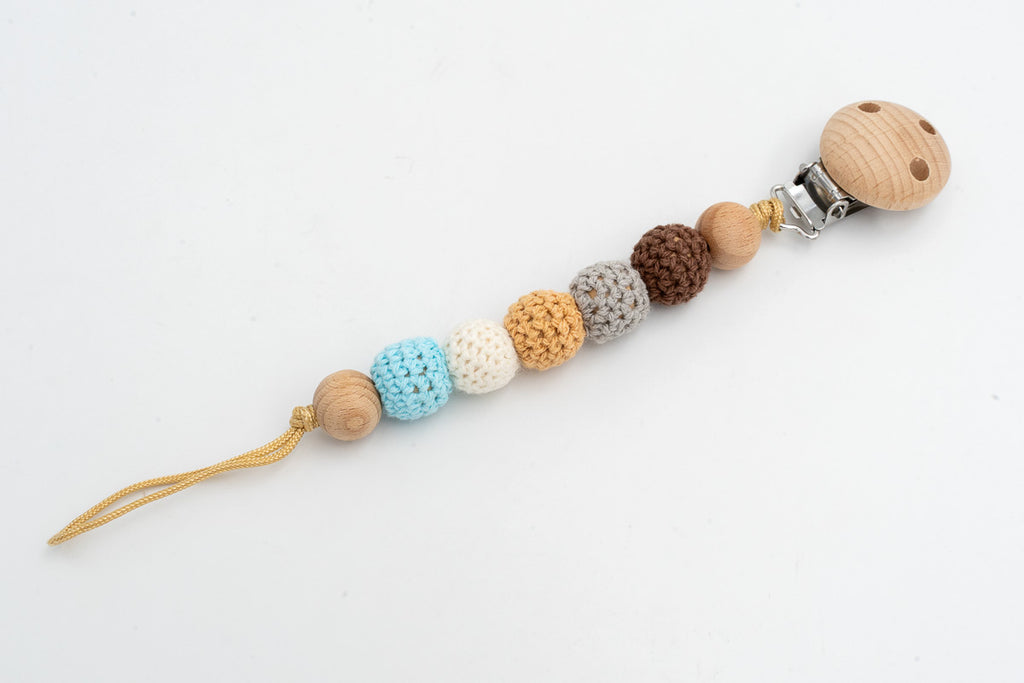 Attache-tétine à perles recouvertes de crochet dans des tons terre, blanc et bleu, avec clip en bois
