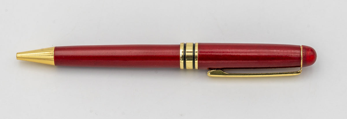 Stylo en bois de finition rougeâtre sans capuchon avec clip et pointe dorés.