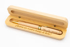 Exemple de stylo en bois clair aux détails dorés dans un étui ouvert gravé pour un témoin de mariage.