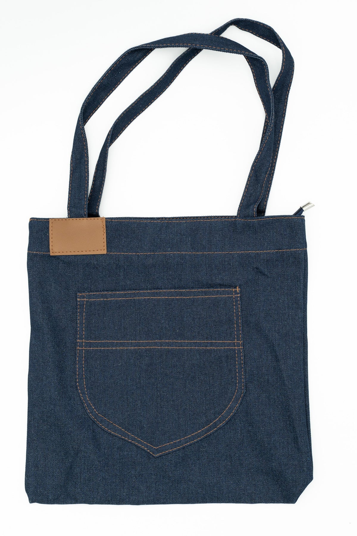 Vista trasera de bolso vaquero con bolsillo grande y parche rectangular de polipiel marrón.