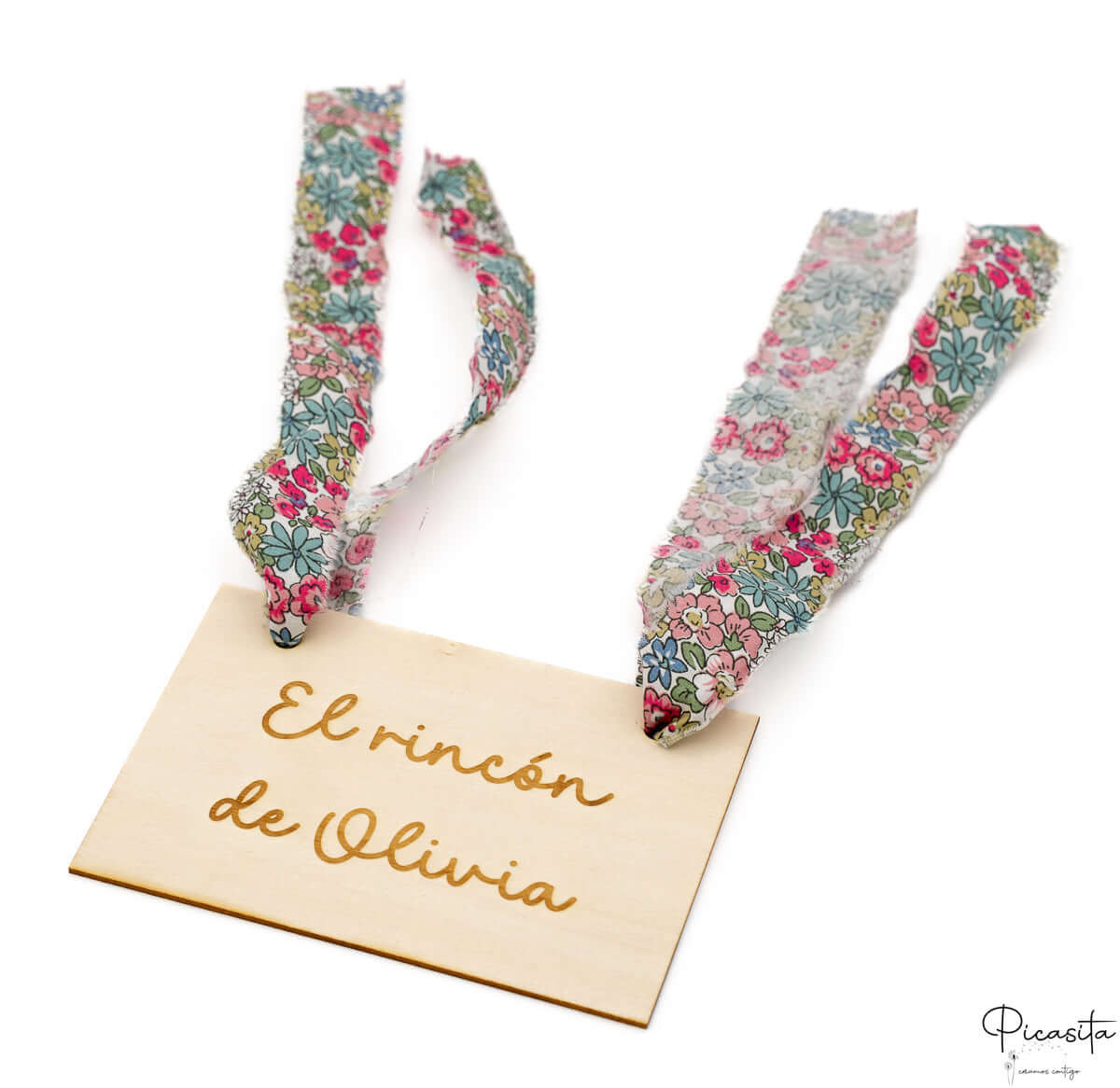 Cartel de madera con nombre Olivia y cintas de tela con estampado floral.