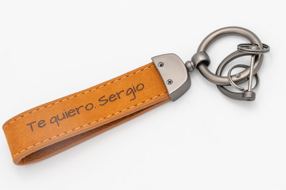 Reverso de llavero de cuero personalizado con frase grabada y tornillos de fijación metálicos.