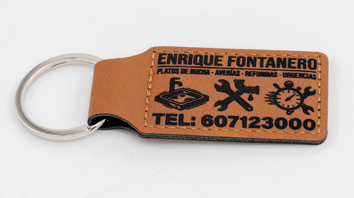 Porte-clé rectangulaire marron avec logo et texte d'un service de plomberie.