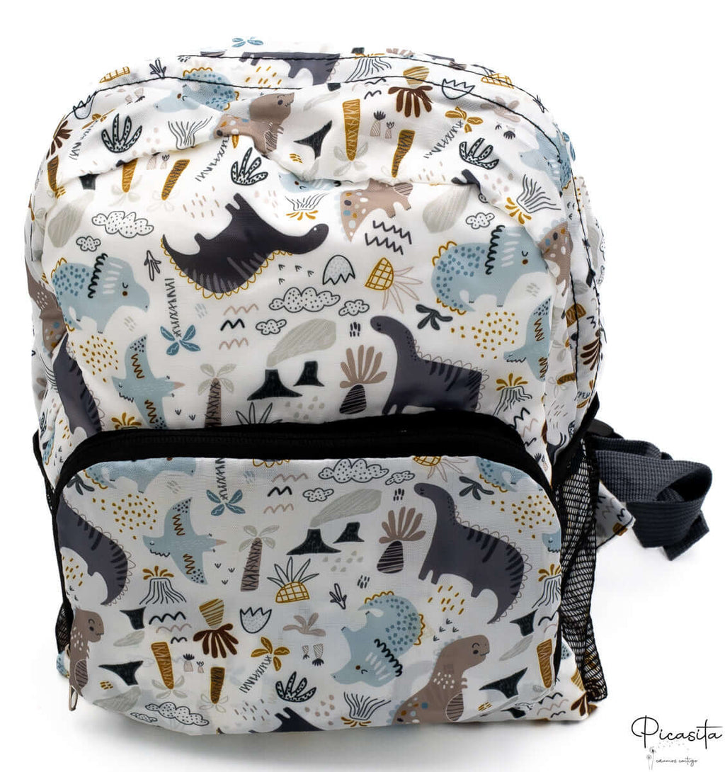 Mochila infantil blanca con estampado de dinosaurios en tonos azules, grises y marrones.