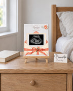 Aperçu simulé : Lettre de bébé  sur Toile, 15 × 20 cm, avec échographie synthétique illustrative. Présentation sur un chevalet de 20 cm posé sur une table.