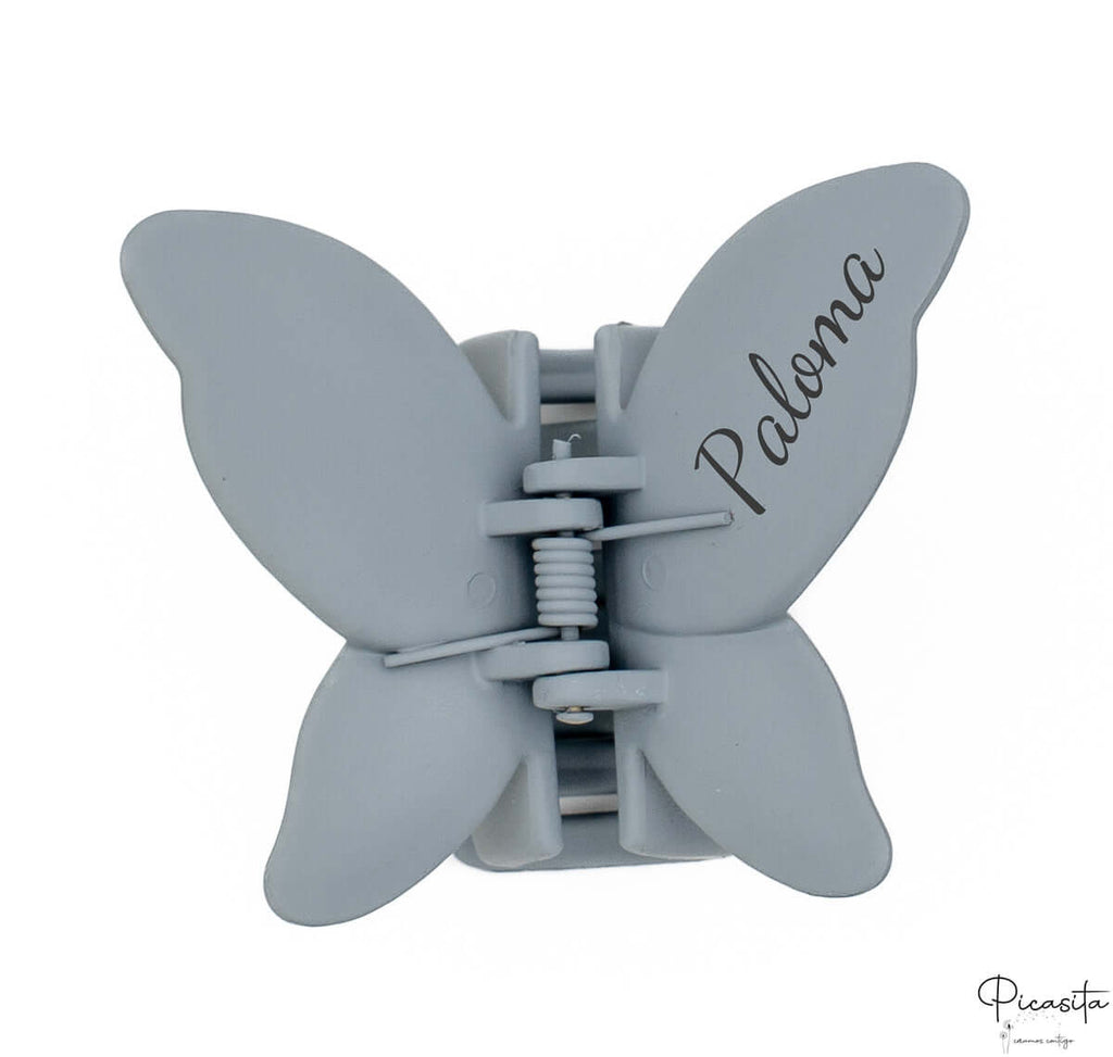 Pinza de pelo mariposa azul grisáceo con el nombre Paloma grabado mediante láser en el ala.