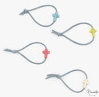 Cuatro pulseras grises infantiles con cuentas de silicona en forma de cruz de varios colores.