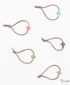 Cinco pulseras elásticas de color malva con motivos de cruces en silicona de tonos variados.