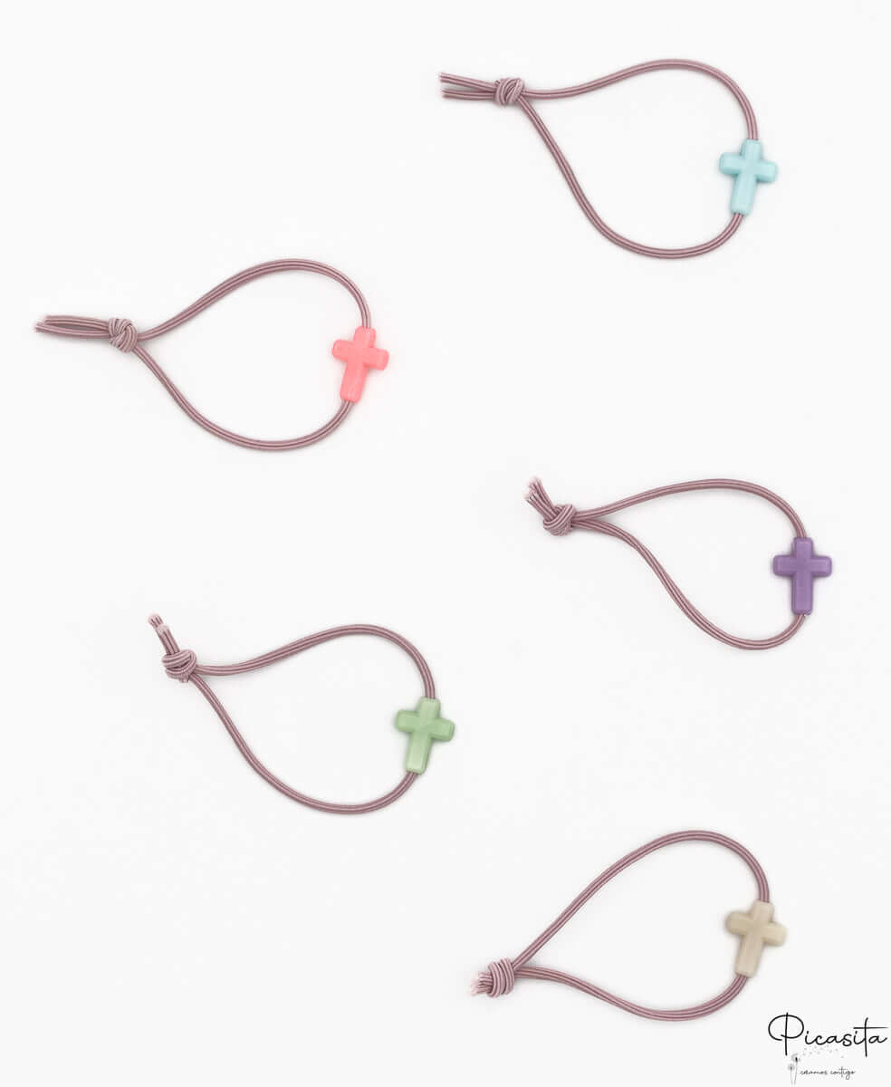 Cinco pulseras elásticas de color malva con motivos de cruces en silicona de tonos variados.