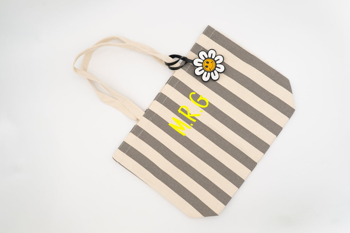 Sac de piscine à rayures grises et blanches orné d’une breloque marguerite