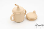 Vaso infantil beige con accesorios desmontables de silicona de grado alimentario.